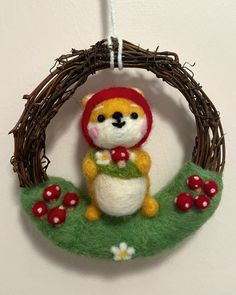 a small stuffed animal is hanging on a wreath with mushrooms and grass in the foreground