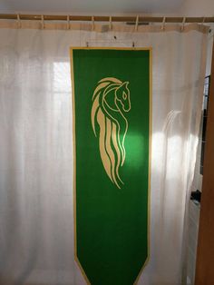 a shower curtain with a green and white horse head on it's side in front of a window