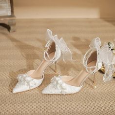 two pairs of white shoes with bows and pearls on the toes are sitting on a carpet