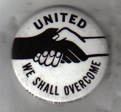 we shall overcome button with handshake and the words united we shall overcome on it