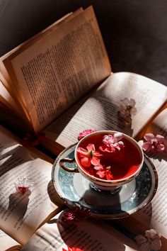 a cup of tea sitting on top of a saucer next to an open book