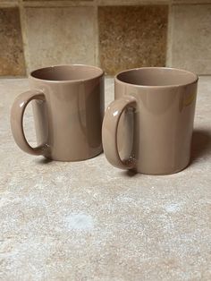 two coffee mugs sitting next to each other on a counter