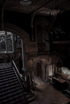 an old fashioned house with stairs and chandelier in the dark, lit room