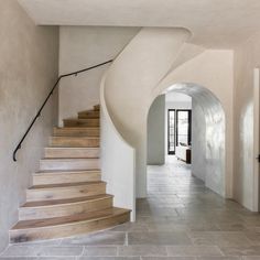 a long hallway with stairs leading up to the second floor and another room on the other side