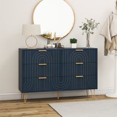 a blue dresser with gold handles in a white room next to a mirror and coat rack