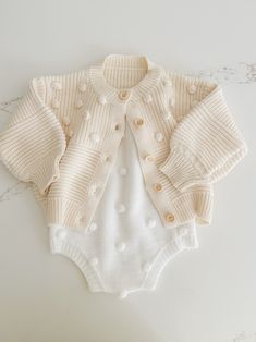 Soft and cozy, this stunning knit cardigan is the perfect addition to your little ones closet. Tiny Pom Pom appliqués all over. Textured pattern with front buttons. Knitted Cotton Button-up Cardigan, Button-up Knitted Cotton Cardigan, Cute Winter Button-up Cardigan, Cute Soft Knit Outerwear For Fall, Playful Cotton Knitted Cardigan, Cute Soft Knit Fall Outerwear, Cute Cotton Cardigan With Button Closure, Cute Button-up Sweater For Winter, Cute Cream Soft Knit Sweater