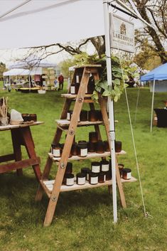 a wooden ladder with jars on it sitting in the grass next to a table and tent