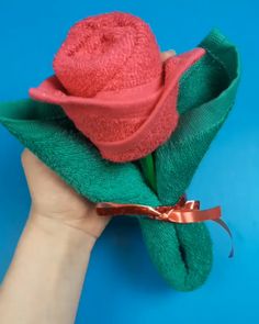 a hand holding a towel wrapped in green and pink fabric with a rose on it