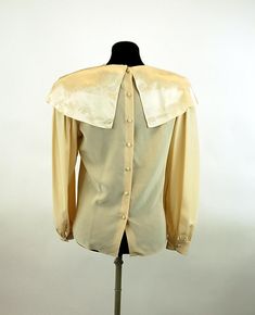 "This is a romantic 1980s blouse made of 100% silk with a large cape collar that is embroidered and features stunning open work. The ivory colored silk is so soft and luxurious! The satin collar gleams in the light. I love the small covered buttons down the back and at the cuffs. It is really an exquisite blouse! Made in the Philippines. Label is Belle Femme by Susan Trout. Size 8. It is generously size, like many blouses from the 80s. Please check measurements. Excellent condition. Measurements Silk Cream Evening Blouse, Cream Silk Evening Blouse, Cream Silk Blouse For Evening, Vintage Silk Blouse For Formal Occasion, Cream Satin Top For Formal Occasions, Cream Satin Tops For Formal Occasions, Formal Cream Satin Top, Vintage Gold Silk Top, Elegant Cream Top With Peter Pan Collar