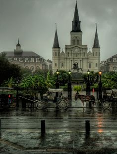 a horse drawn carriage on a rainy day in front of a large building with spires