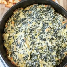 spinach and cheese dip in a cast iron skillet with two slices of pizza on the side