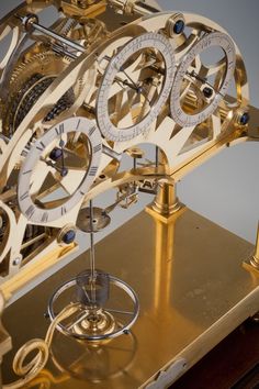 a golden clock with gears on it sitting on top of a table