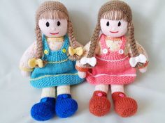 two knitted dolls sitting next to each other on a white surface with one holding the other's hand