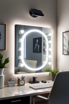 a desk with a chair and a mirror on the wall above it that is lit up