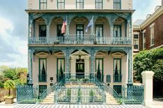 an old house with blue ironwork and green trimmings on the front porch