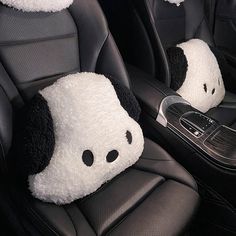 two stuffed panda bears sit in the front seats of a car with headrests