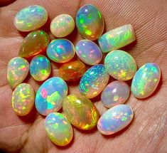 a person is holding some opales in their hand and there are many opals on the palm