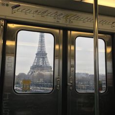 the eiffel tower is seen through two open doors in this train car window