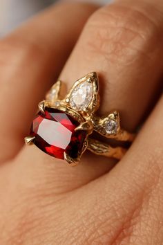 a woman's hand with a red and white diamond ring on her left finger