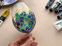 a hand painted wine glass being held by someone