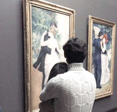 a man and woman looking at paintings on display