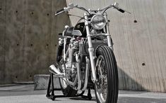 a motorcycle parked in front of a building with a concrete wall behind it and another bike on the ground