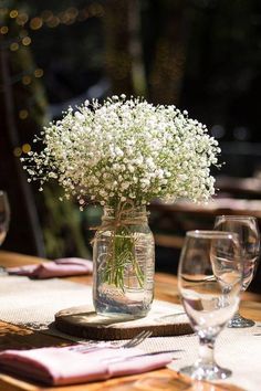 a vase filled with baby's breath sitting on top of a table next to wine glasses