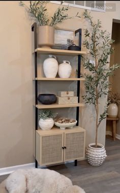 a shelf with vases and other items on it in a room that has wood floors