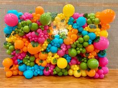 a bunch of balloons that are in the shape of a rainbow ballon sculpture on a wooden floor