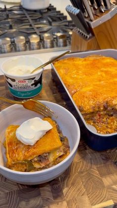 a casserole dish with sour cream on top and a fork in the bowl next to it