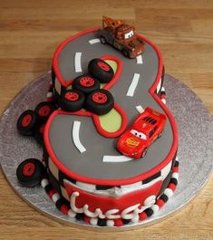 the birthday cake is decorated with cars and trucks