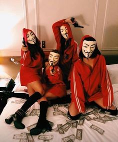 four people in red hoodies and masks sitting on a bed with money all around them