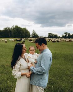 a man and woman holding a baby in a field