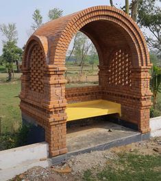 a bench made out of bricks sitting in the middle of a field