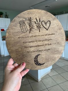 a person holding up a wooden plaque with an image of herbs and spices on it