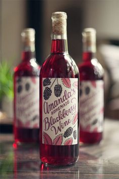 three bottles of homemade blackberry wine sitting on a counter top with the label printed onto it