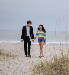 a man and woman walking on the beach holding hands