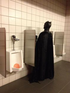 a bathroom with urinals and a batman costume