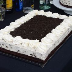 a cake with white frosting and chocolate shavings sitting on top of a table