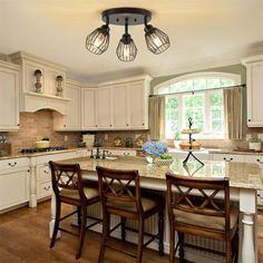 a kitchen with white cabinets and marble counter tops, an island with four bar stools