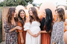 a group of young women standing next to each other in front of giant pink balloons