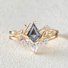 a diamond ring with leaves on it and two pear shaped diamonds in the middle, sitting on a white surface