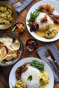 three plates with different types of food sitting on a wooden table next to silverware and utensils