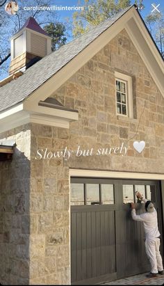 a man painting the side of a house with words above it that read slowly but surely