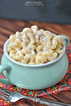 a bowl filled with macaroni and cheese sitting on top of a wooden table