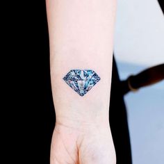 a woman's wrist with a blue diamond tattoo on her left arm and the other hand