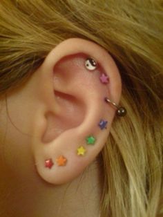 a close up of a person's ear with different colored stars on it