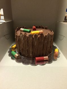 there is a chocolate cake with crayons on it in the shape of a tree stump