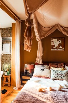 a bed sitting in a bedroom next to a window with drapes on top of it