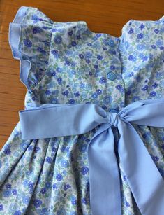 "This beautiful handmade custom dress is made from petite blue floral fabric! The front bodice is lined with blue fabric and buttons in the back. This makes a perfect spring or Easter dress! The length can be customized for your little girl and the dress can be made in a variety of fabrics - just send me a message with your request! I have a size 12 months and and 18 months ready to ship. Features - Sevenberry floral fabric from Robert Kaufman - Double flutter sleeves - Fabric feels crisp and ir Fitted Cotton Floral Dress With Ruffles, Fitted Floral Cotton Dress With Ruffles, Fitted Blue Ditsy Floral Dress, Fitted Blue Floral Dress With Ditsy Print, Blue Fitted Dress With Ditsy Floral Print, Fitted Blue Floral Dress For Garden Party, Blue Floral Dress For Garden Party, Fitted Light Blue Dress With Ditsy Floral Print, Blue Ruffle Dress For Garden Party